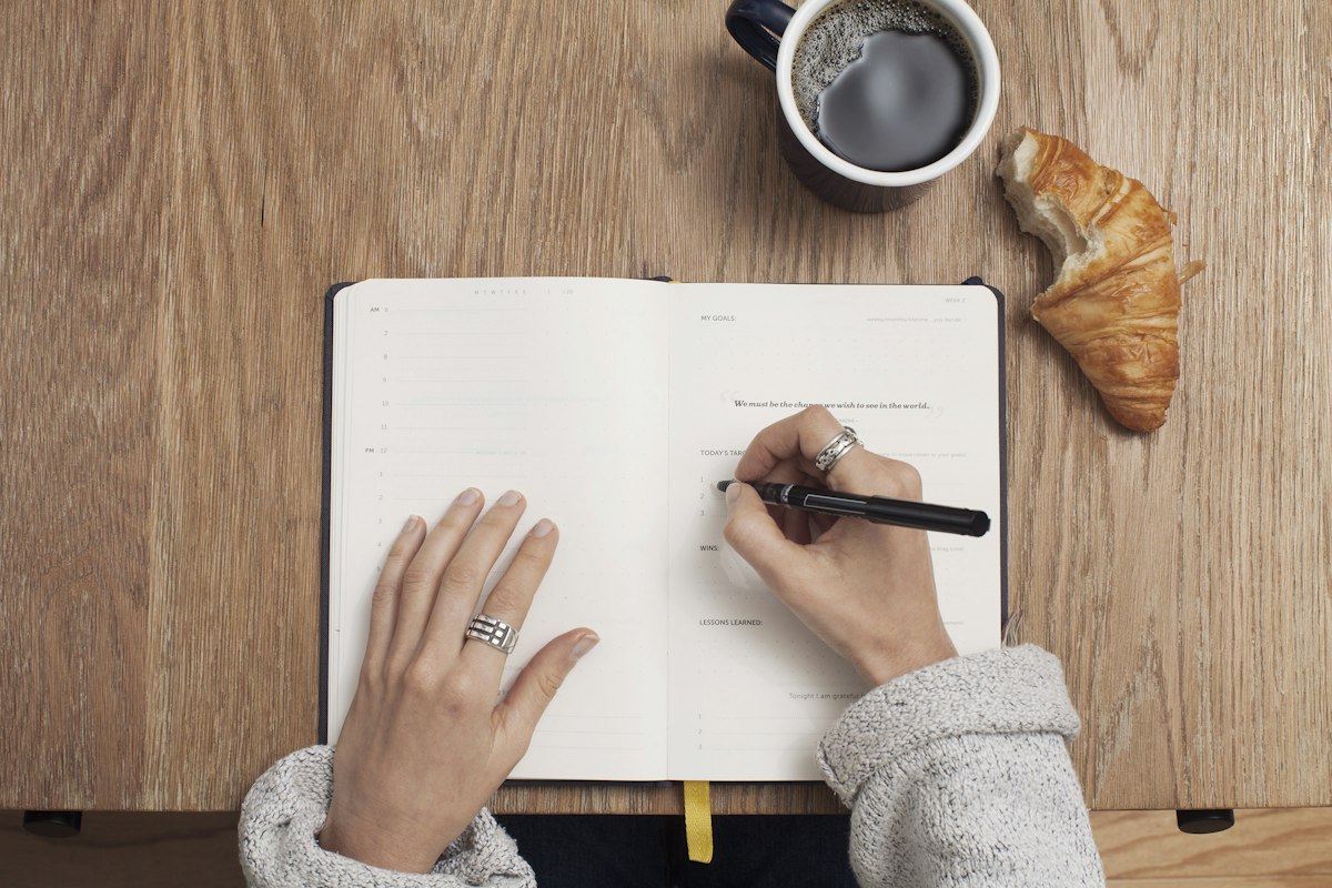 Handwritten weekly priorities on a notepad beside a laptop